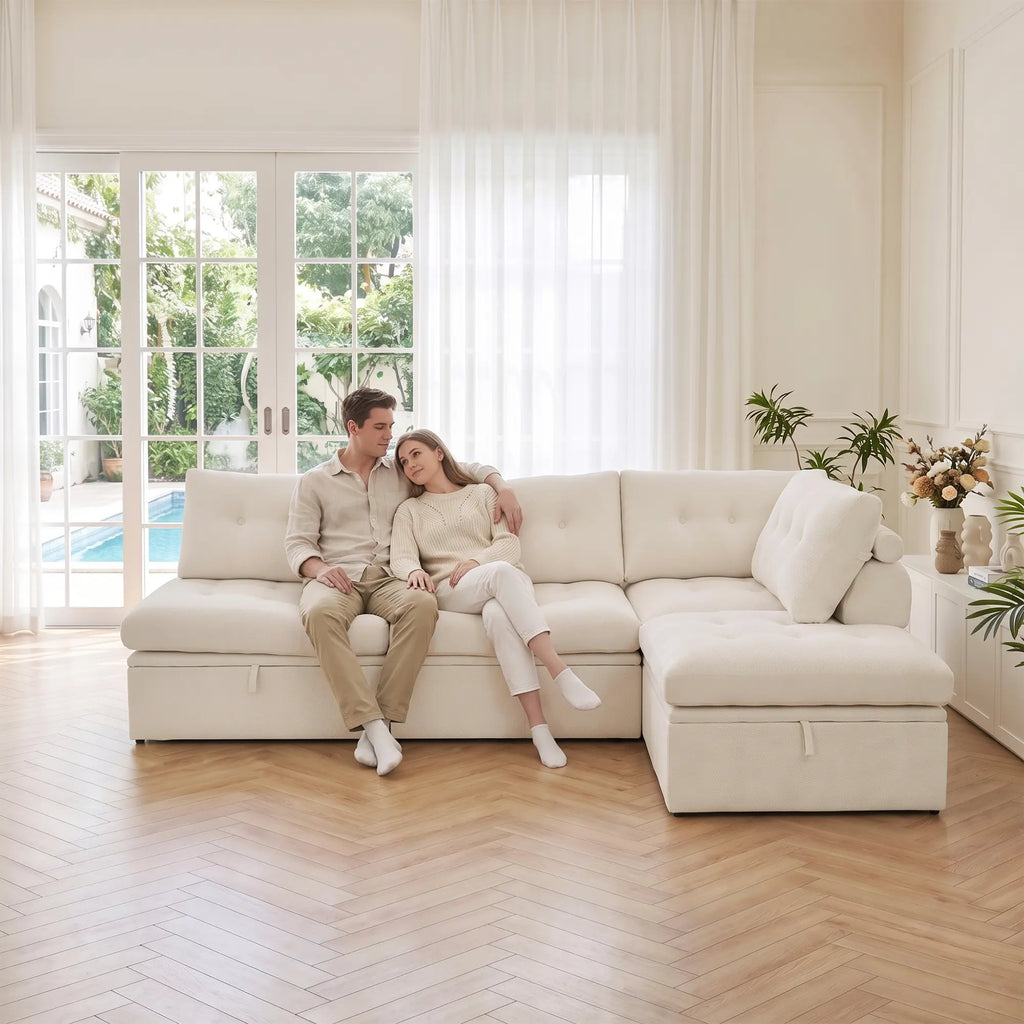 Side level view of a couple sitting on a Korser beige 3-seater L-shaped modular sectional sofa with backrests.