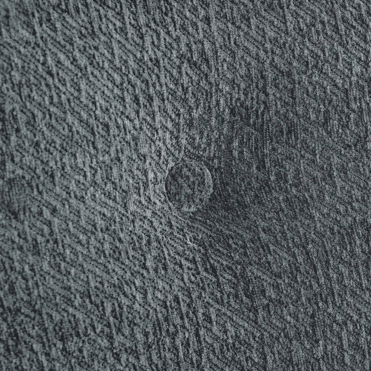 Macro close-up of the Korser grey fabric sofa, highlighting the detailed woven texture of the upholstery.