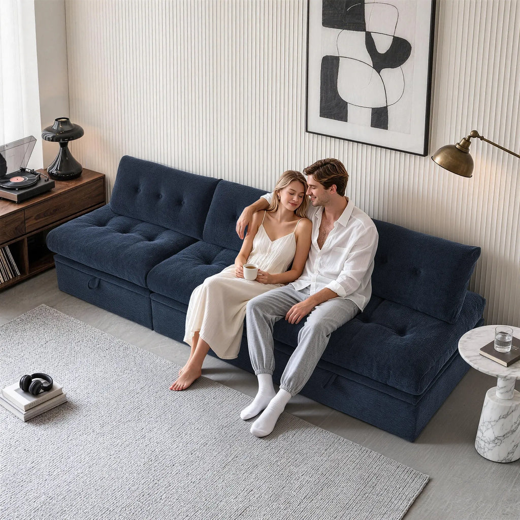 Side level view of a couple sitting on a Korser navy blue 3-seater straight modular storage sofa with backrests.